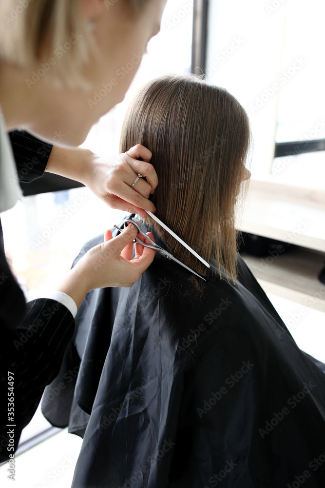 Hairdresser cutting hair in salon closeup
