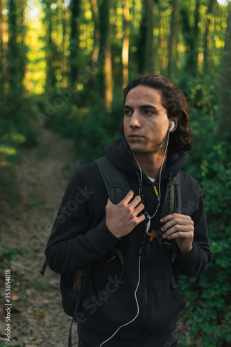 young mountaineer wearing backpack and headphones is curious about his surroundings