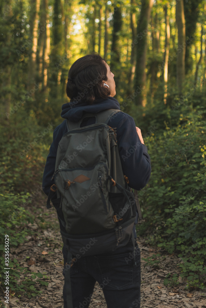 young mountaineer wearing backpack and headphones is curious about his surroundings young mountaineer wearing backpack and headphones is curious about his surroundings