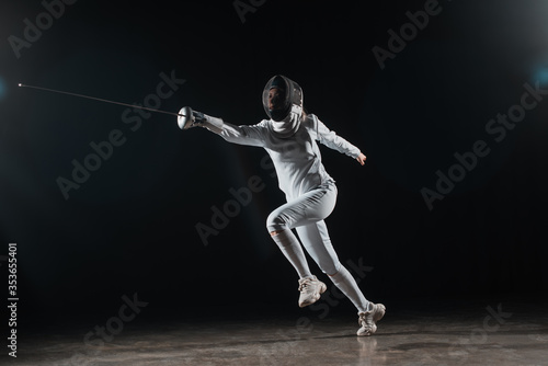 Fencer holding rapier while training on black background