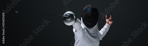 Panoramic orientation of fencer training with rapier isolated on black photo
