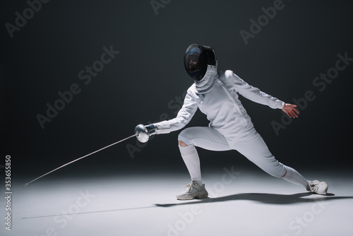 Fencer training under spotlight on black background