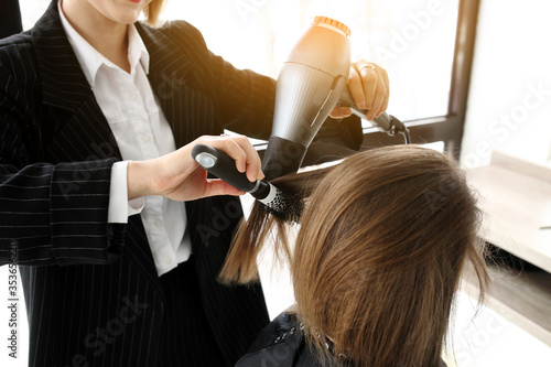 stylist drying woman hair in salon