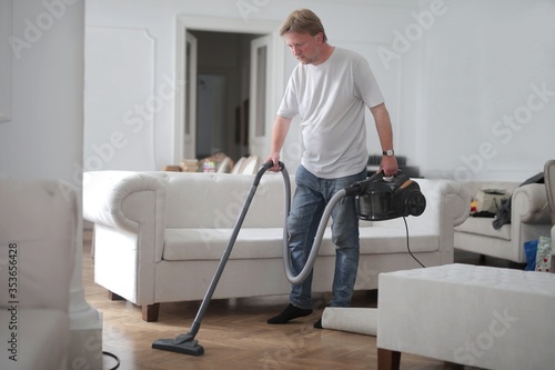 man cleans house with vacuum cleaner