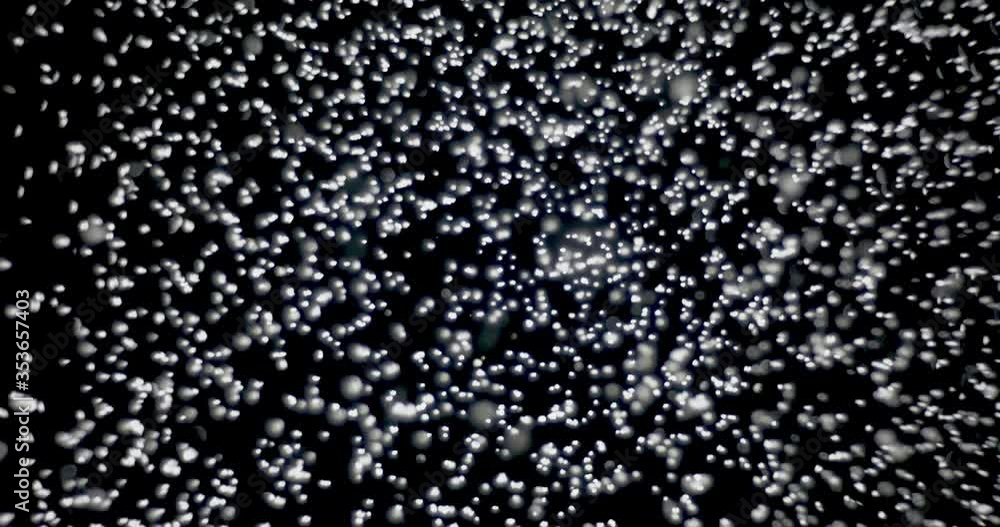 White snowflakes falling from the sky fast against an isolated black background White snowflakes falling from the sky fast against an isolated black background