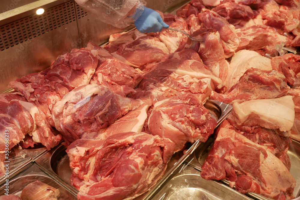 Fresh raw pork meat lies on the counter. A wide range of pork in a butcher's shop. An abundance of beautiful red raw pork meat.
