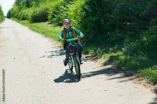 Boy on bicycle at summer asphalt road. Kid cycling outdoors. Summer sport activity concept. Soft focus