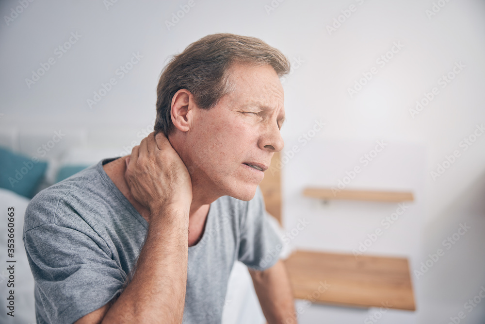 Upset mature man suffering pain in neck Upset mature man suffering pain in neck