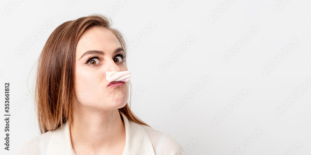 Young woman making mustache with sweet candy marshmallow on white background. Copy space. Banner for site. Young woman making mustache with sweet candy marshmallow on white background. Copy space. Banner for site.