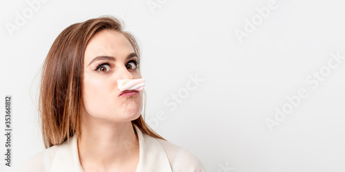 Young woman making mustache with sweet candy marshmallow on white background. Copy space. Banner for site.