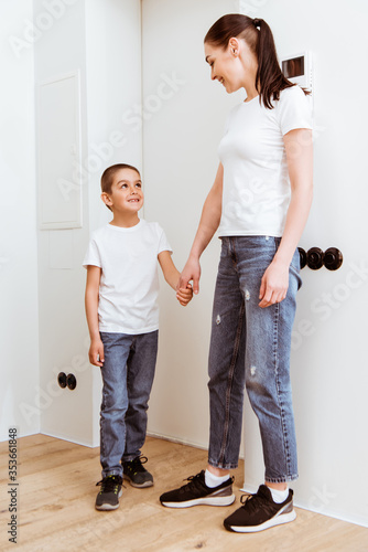 Mother and kid smiling at each other while holding hands in hallway