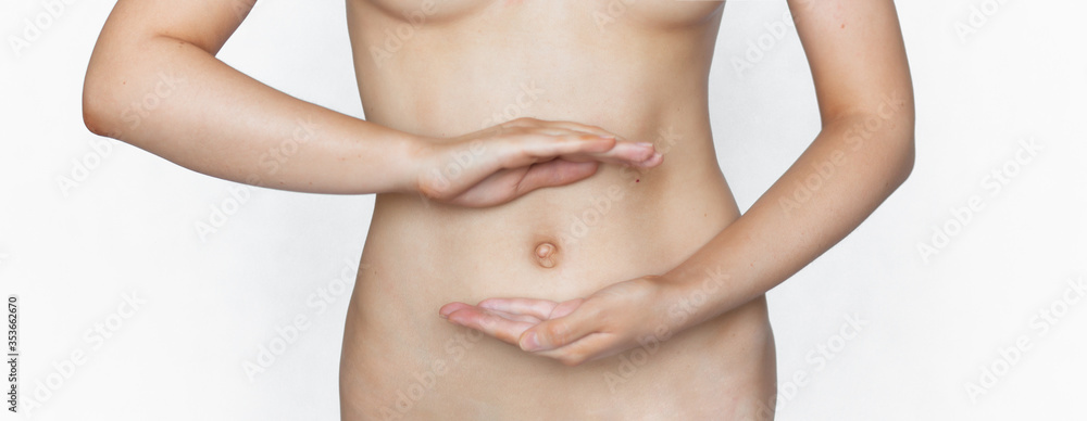 The girl holds hands on a slender stomach in a protective figure. Healthy digestion, early pregnancy, prebiotic health. Healthy lifestyle concept. Banner crop The girl holds hands on a slender stomach in a protective figure. Healthy digestion, early pregnancy, prebiotic health. Healthy lifestyle concept. Banner crop