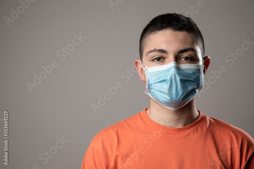 Ragazzo giovane con mascherina , isolato su sfondo grigio © alex.pin