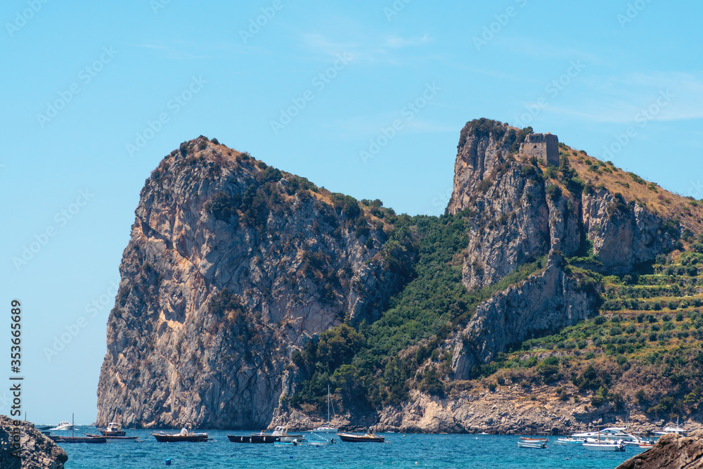 View from the public beach to the mountains. The small town of Nerano. Cove with ships and boats. Summer day. Vacation and vacation concept in Italy. Naples coast