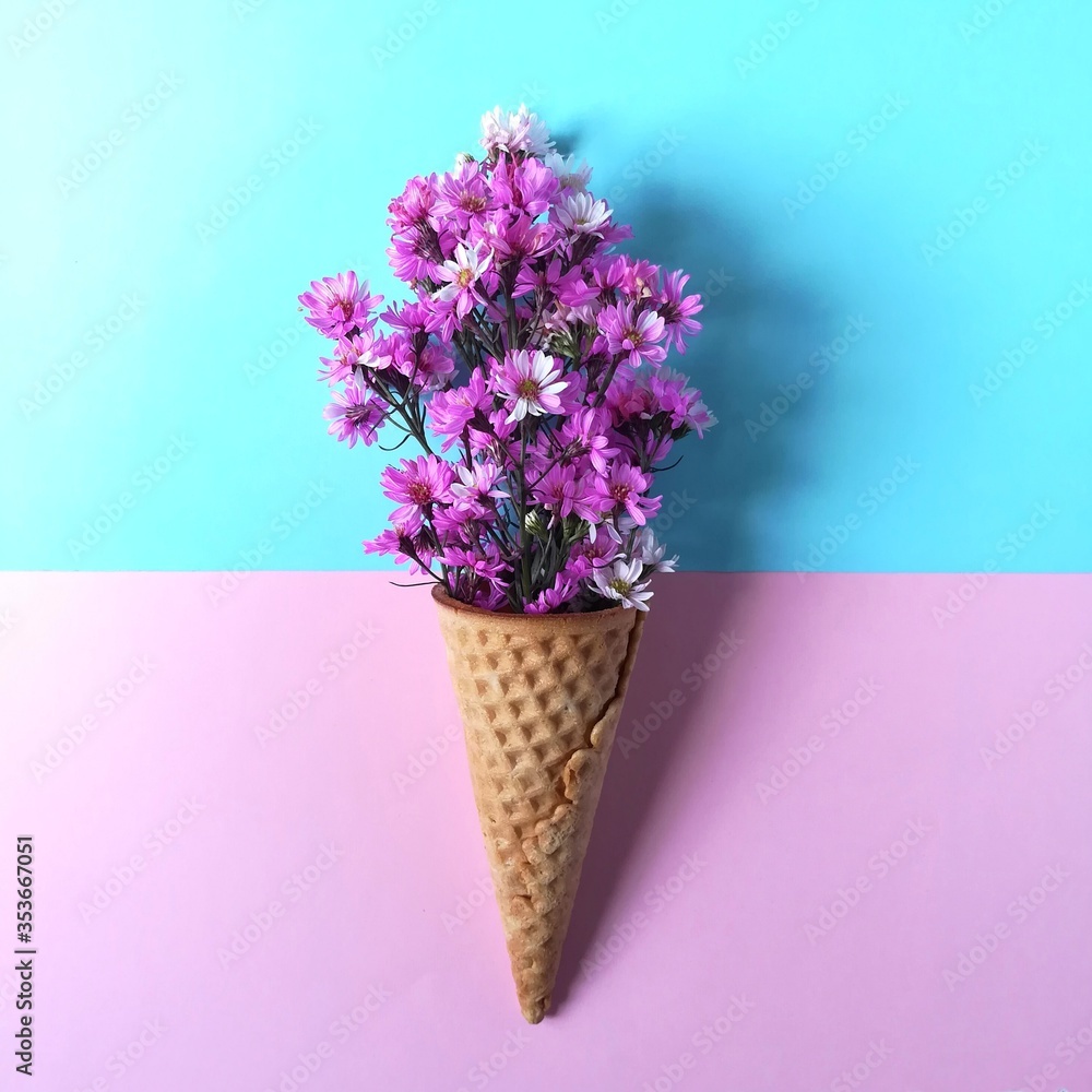 Cutter flower and ice cream cones on pastel colored background. Pink flower in a ice cream cones.