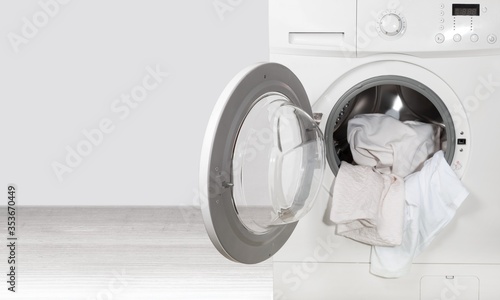 Fotografie Washing machine with different laundry on background