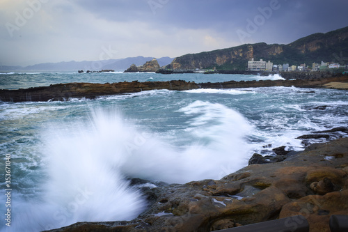 The waves in the sea blow the sea water to hit the rocks on the coast.