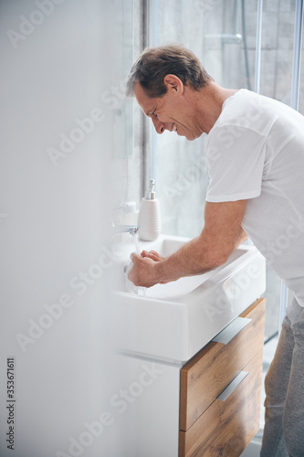 Pleased man leaning over a ceramic wash basin