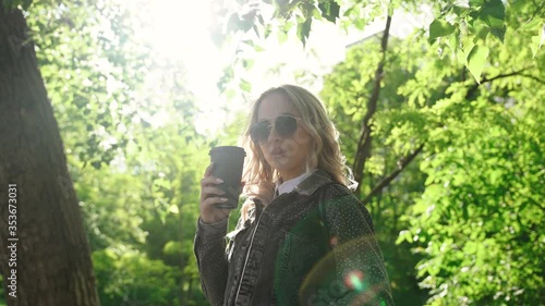 Young blonde woman drinking coffee in the park