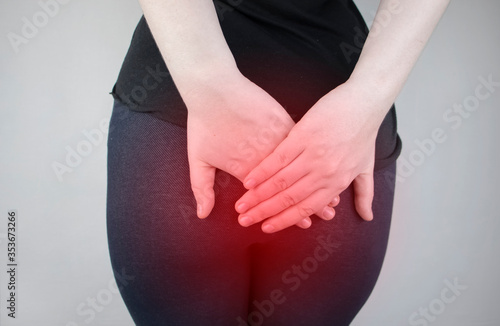 A woman holds his hands to the ass feeling pain. Conversion of pain in the rectum, hemorrhoids and pain in the excretory system of the body. Frequent bowel movements. photo