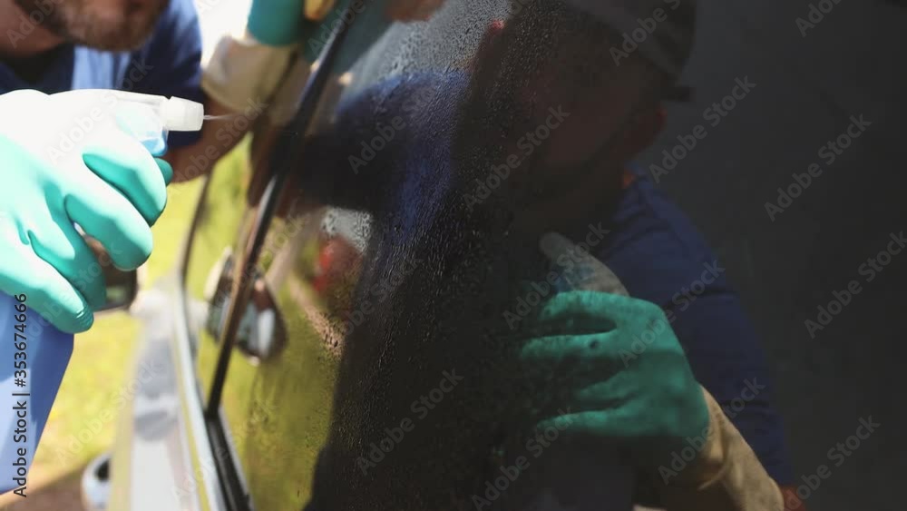Professional car cleaning. A man in gloves cleans and wipes the tinted glass of the car and is reflected in it. Datailing Professional car cleaning. A man in gloves cleans and wipes the tinted glass of the car and is reflected in it. Datailing