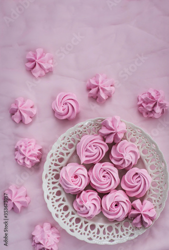 Pink meringues on plate, colorful background, top view