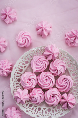 Pink meringues on plate, colorful background, top view