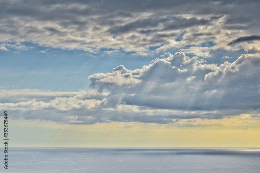 Sun shines through rain clouds over Tasman sea horizon