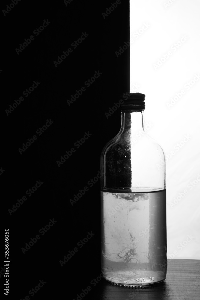 A small bottle on a black and white background. Half black and half white A small bottle on a black and white background. Half black and half white