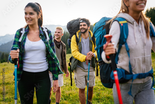 Group of happy friends with backpacks hiking together