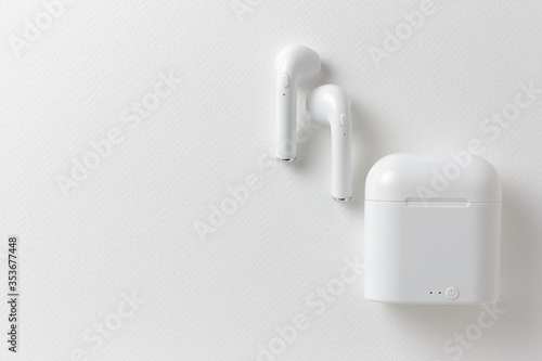 Modern wireless earphones and charging case on white background, flat lay