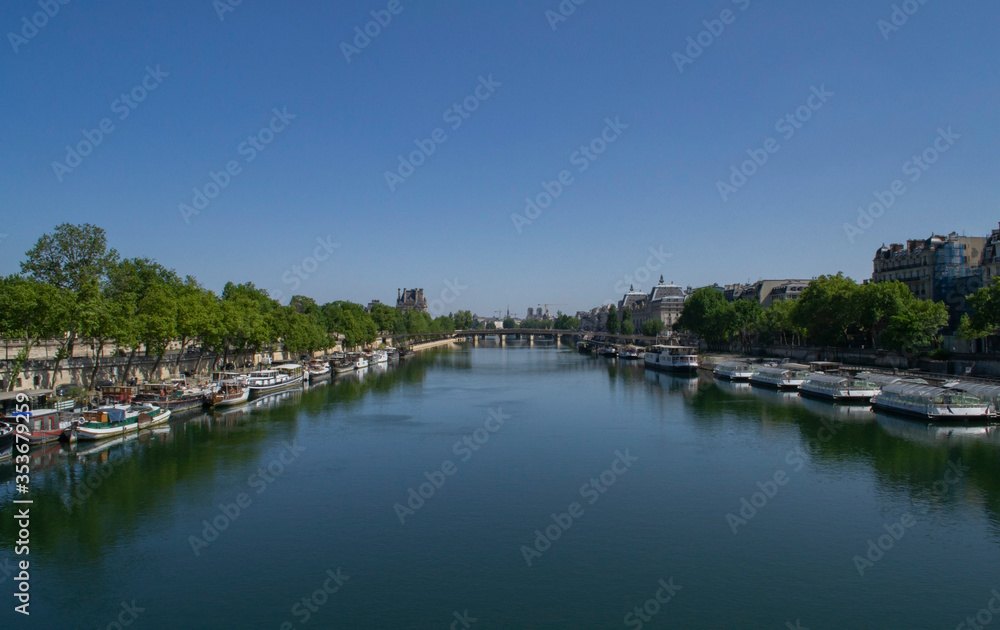 view of the Seine river with two banks and boats on it and a bridge in Paris