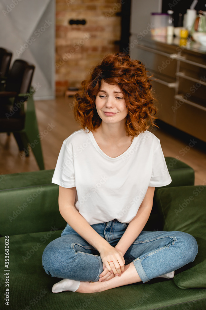 Obraz premium attractive and curly woman sitting on sofa