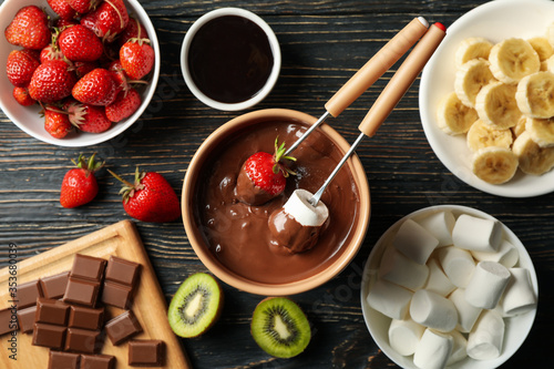 Composition with ingredients for chocolate fondue on wooden background. Cooking fondue photo