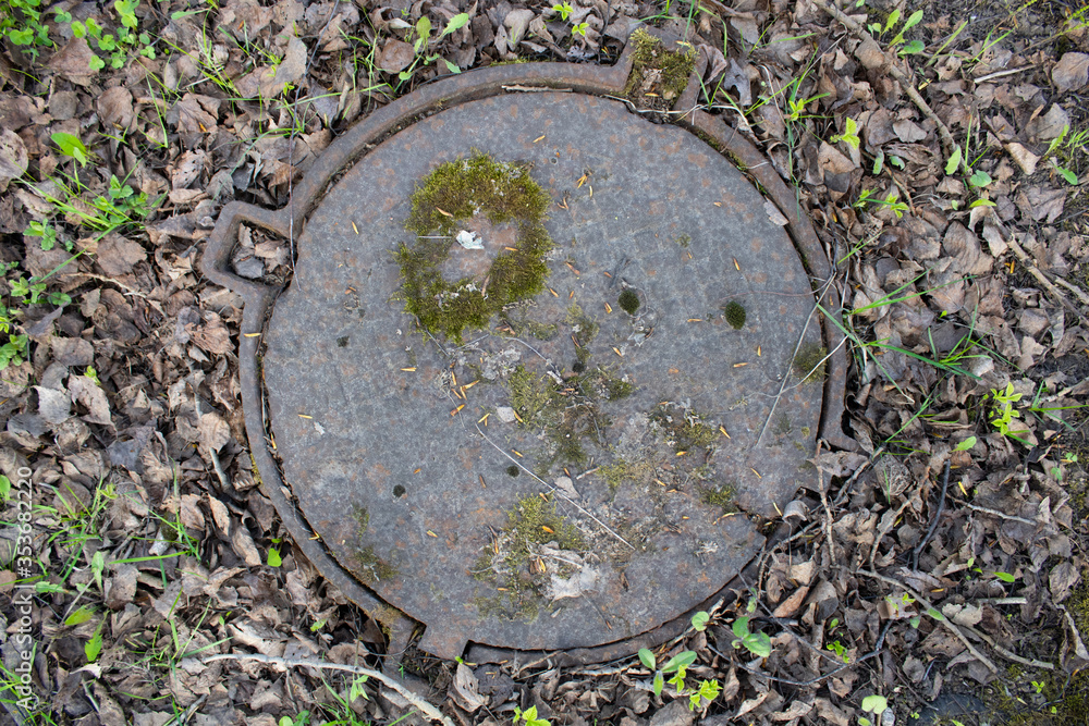 Moss-covered antique sewer manhole cover. Moss-covered antique sewer manhole cover.