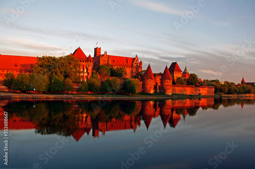 Mighty castle of the Teutonic Knights Order in Malbork (Poland, historical Prussia) on a dawn. The biggest brick gothic fortress in the world, UNESCO world heritage site. Fairy-tale medieval castle. 