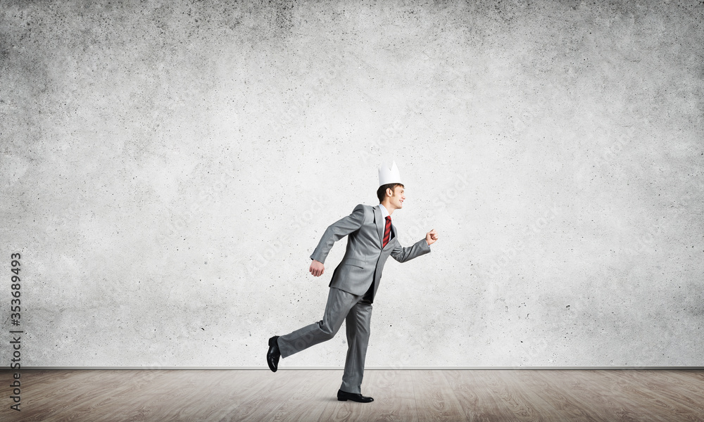 King businessman in elegant suit running in empty room with wooden floor King businessman in elegant suit running in empty room with wooden floor