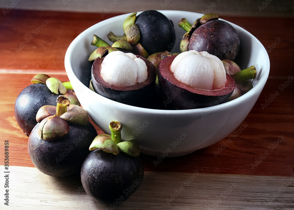 Fototapeta premium fresh purple mangosteens in white bowl, an exotic fruit for healthy living , organic mangosteens 