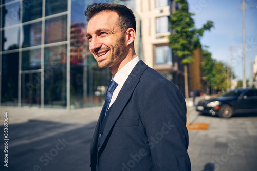 Young brunette businessman walking along street in spring