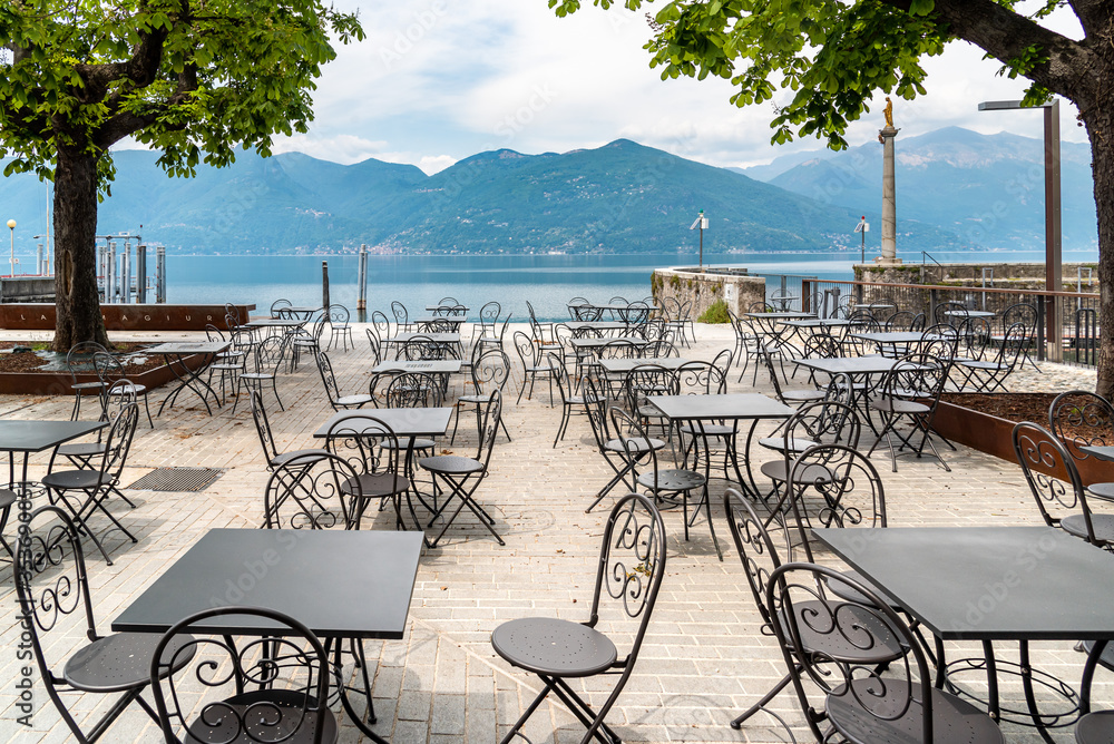 Tables and chairs of street cafe on lake Maggiore lakefront in Luino, Italy
