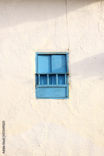 Blue simple, rural, and beautiful windows against a white rustic wall