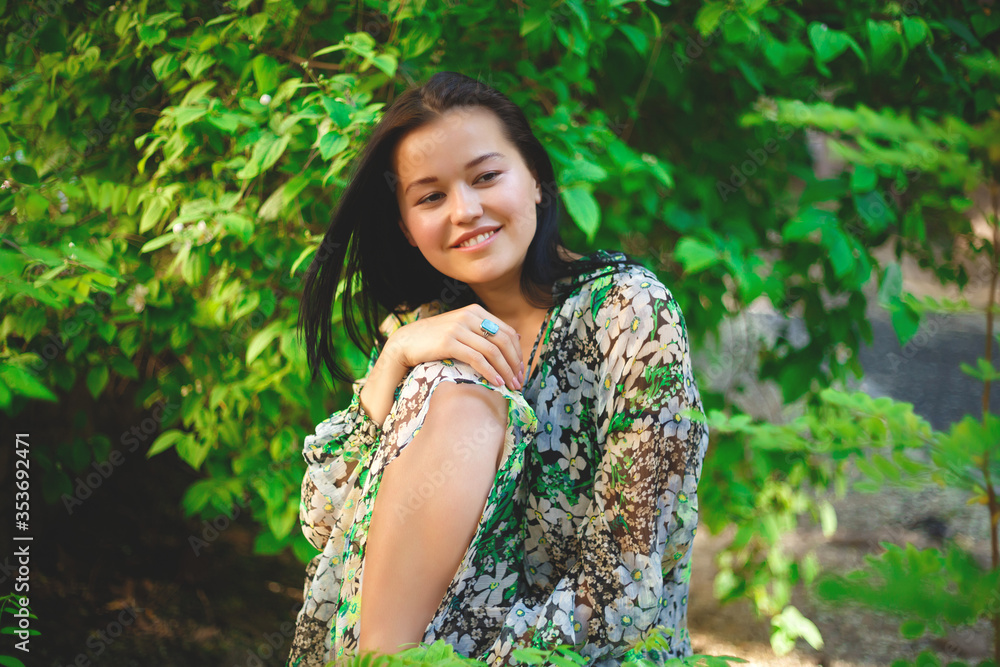 portrait of a beautiful smiling brunette on a background of greenery portrait of a beautiful smiling brunette on a background of greenery