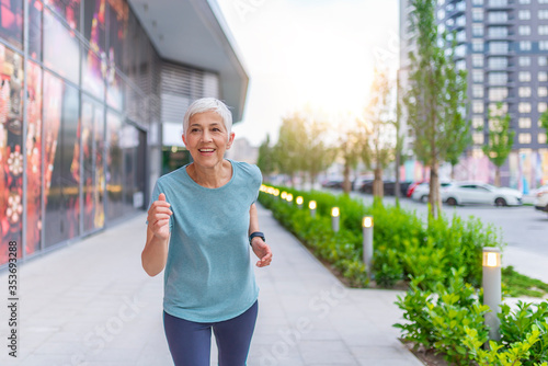 Joyful Senior Woman in Fitness Outfit Get Morning Running. Senior Woman Doing Her Jogging Outside at Public Park Trail. Mature Caucasian Woman Exercising at Park - Fitness, Sport, Training