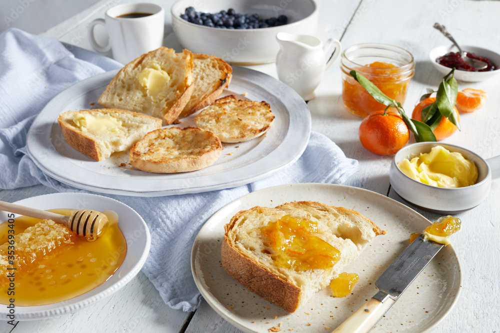Plates of toast with butter and marmalade, dishes of honey, butter and jams. Plates of toast with butter and marmalade, dishes of honey, butter and jams.