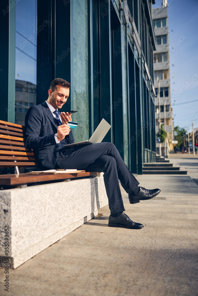 Brunette male laughing while talking on phone outside Brunette male laughing while talking on phone outside