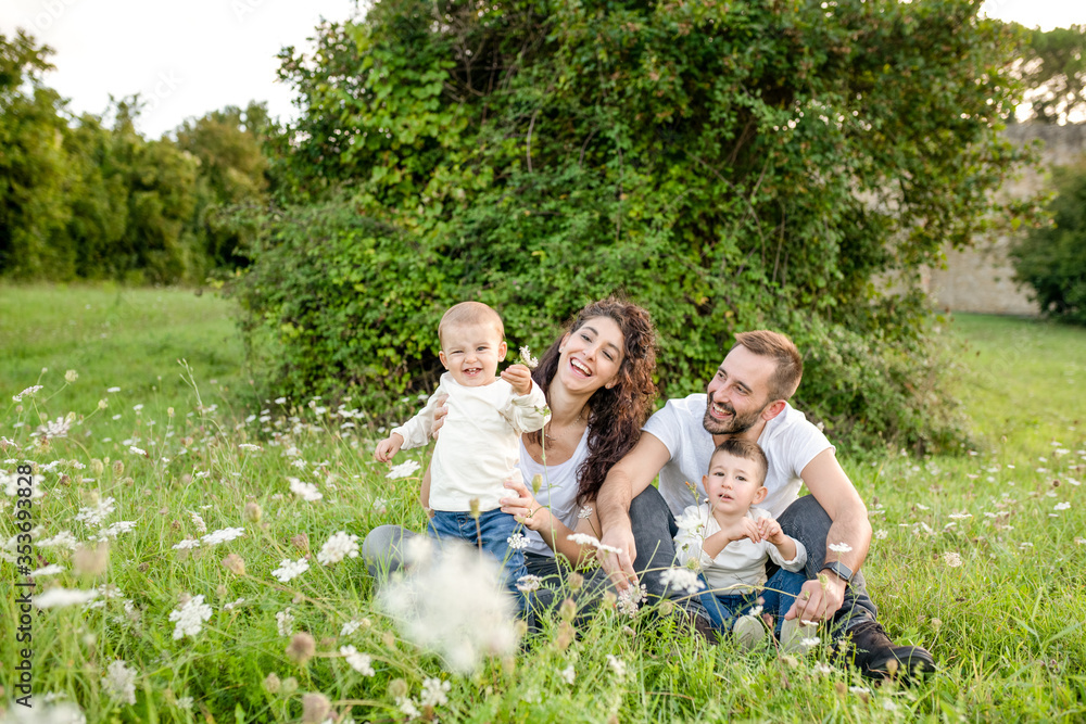 Portrait of family with two children sitting in a meadow, smiling at camera. Portrait of family with two children sitting in a meadow, smiling at camera.