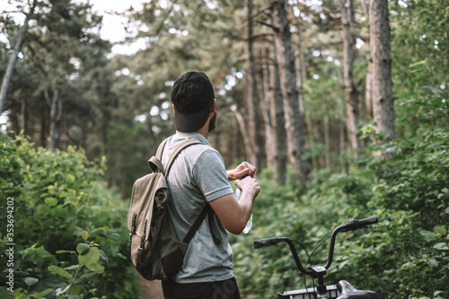 Young man with backpack cycling on a forest path, active lifestyle, playing sports in nature.