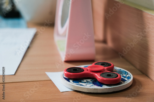 Red fidget spinner isolated on a wooden table