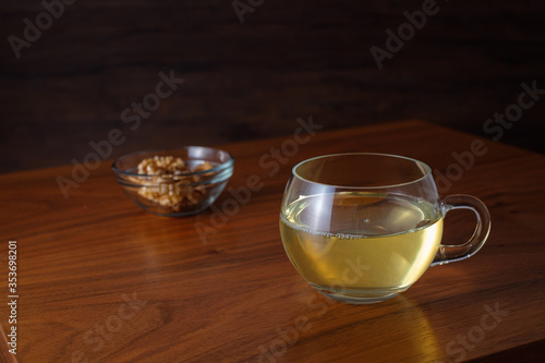 Glass cup of green tea with walnuts on table