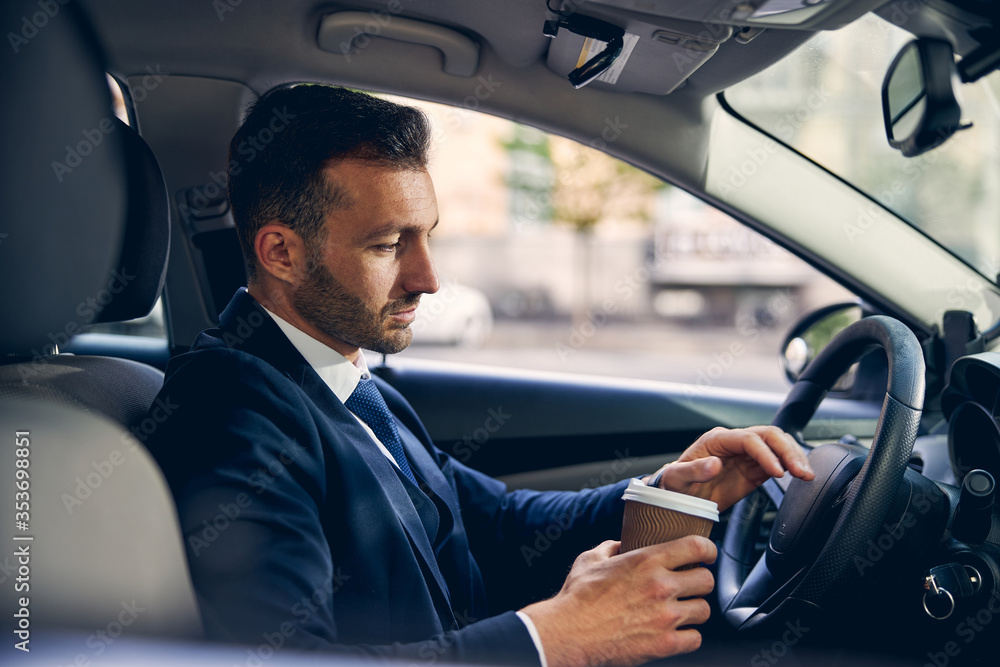 Handsome Caucasian male staying in car with drink